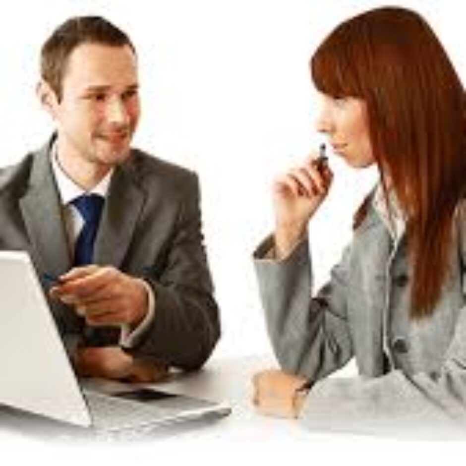 A man and woman sitting at a table with a laptop.