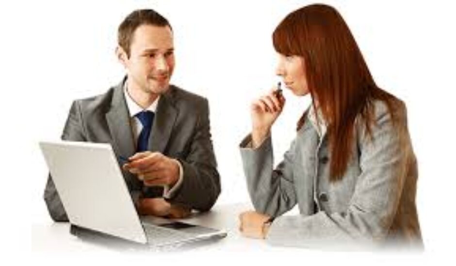 A man and woman sitting at a table with a laptop.