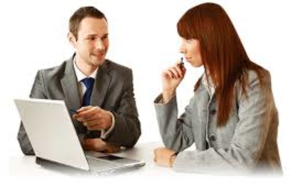 A man and woman sitting at a table with a laptop.