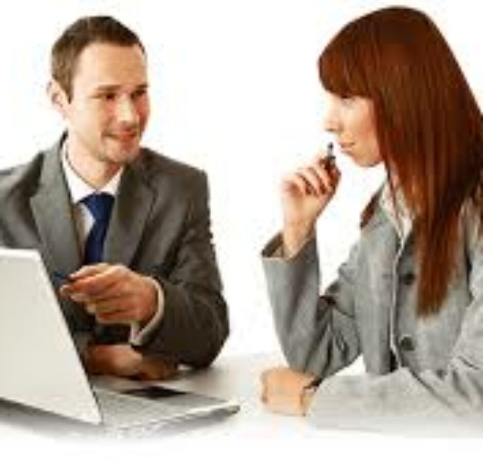 A man and woman sitting at a table with a laptop.