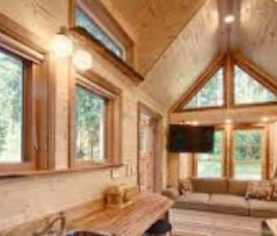 A living room with wood paneling and windows.