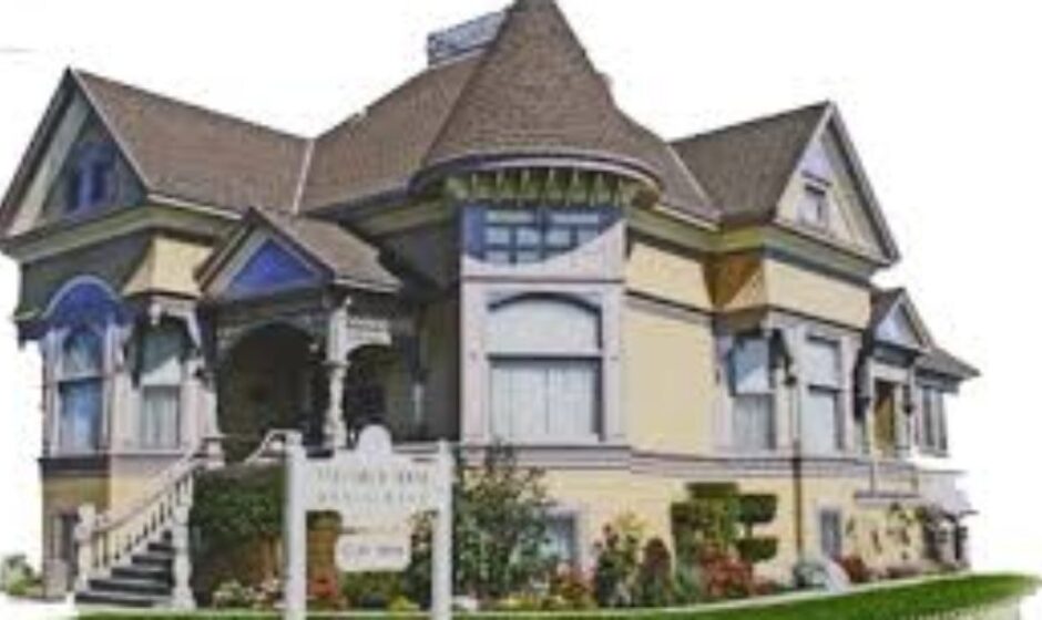 A large house with many windows and flowers in front of it.