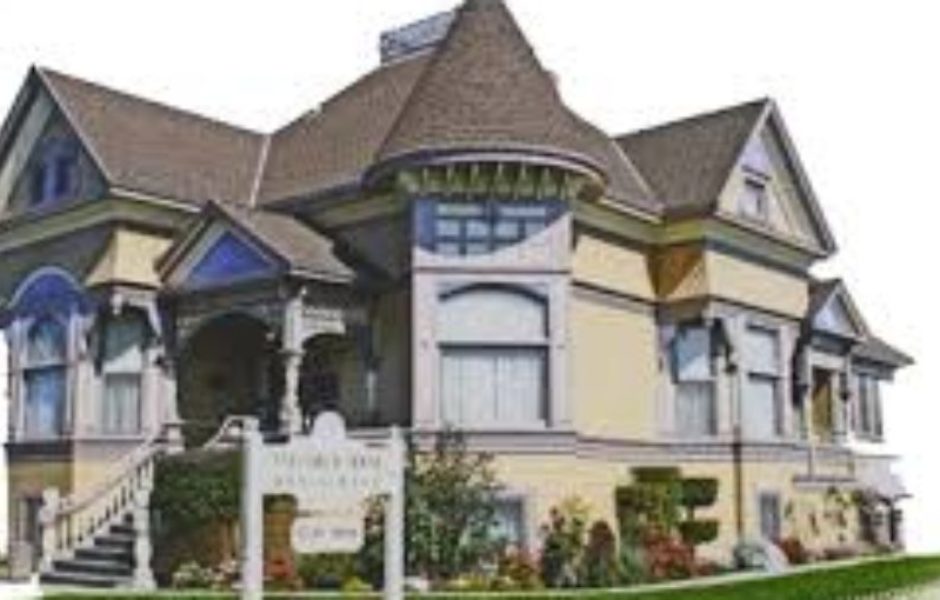 A large house with many windows and flowers in front of it.