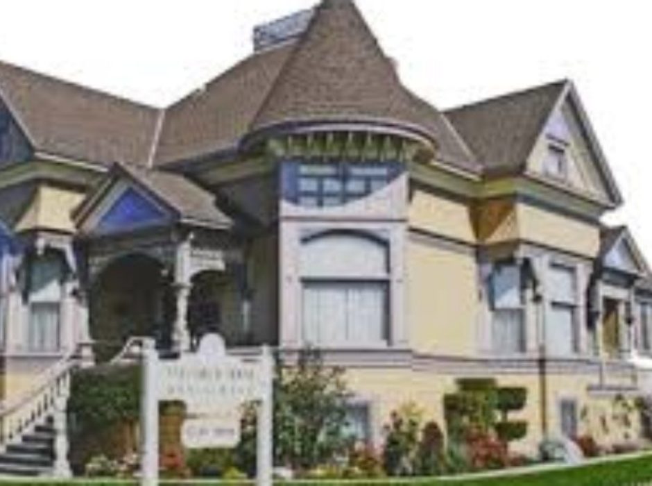 A large house with many windows and flowers in front of it.