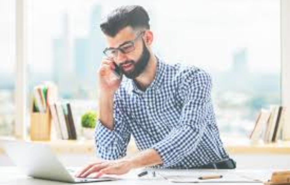 A man sitting at his desk on the phone