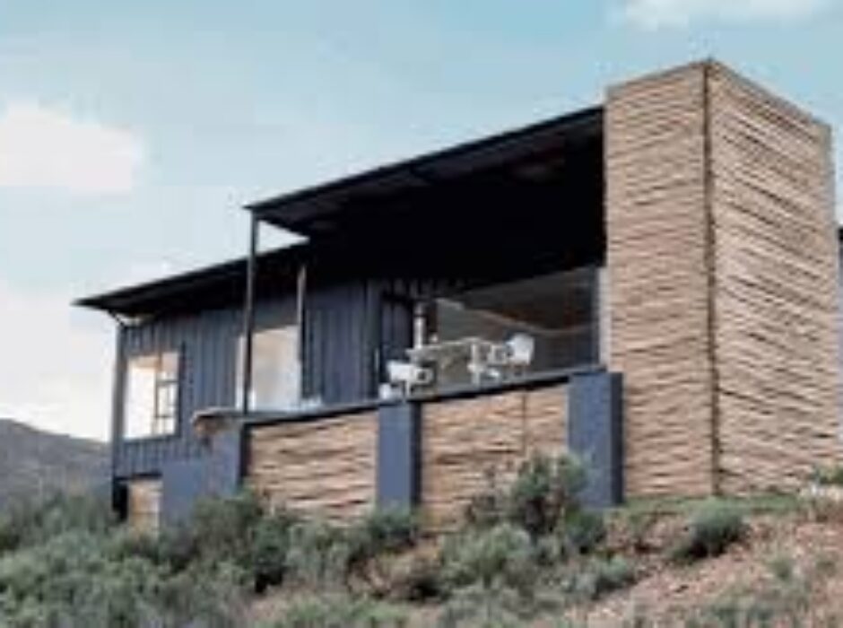 A house built from shipping containers on top of a hill.