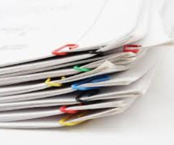 A stack of newspapers with colored paper clips.