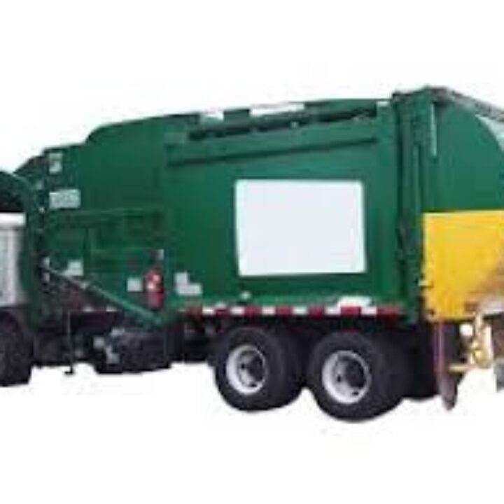 A garbage truck is parked next to the side of it.