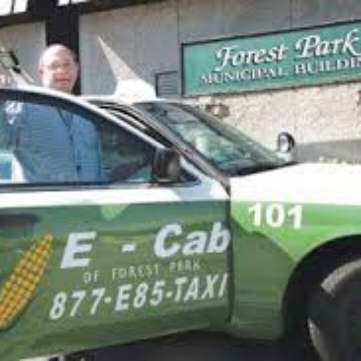 A man standing in front of a green taxi cab.